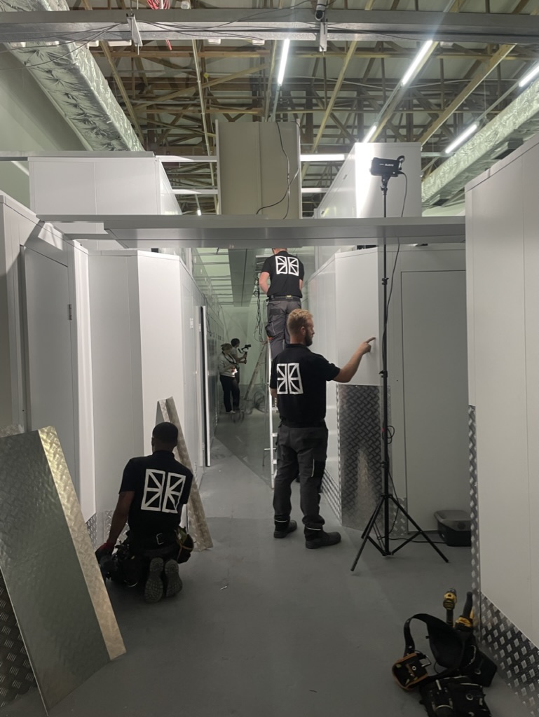 Team constructing modern self-storage units at a flexistore facility in stellenbosch. Workers assembling secure and customizable storage spaces under well-lit conditions with visible industrial details.